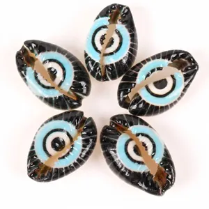 Macro detail of DIY cowrie shell beads featuring a vibrant blue and black evil eye pattern design