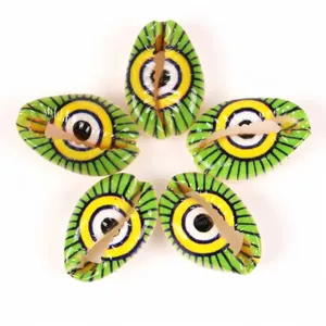 Detail view of five green and yellow eye-patterned cowrie shell beads for DIY jewelry