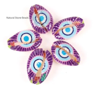 Macro detail of purple cowrie shells with evil eye pattern for DIY jewelry making.