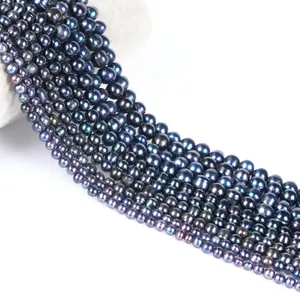 Rangs de perles noires lustrées presque rondes pour création de bijoux DIY sur fond blanc