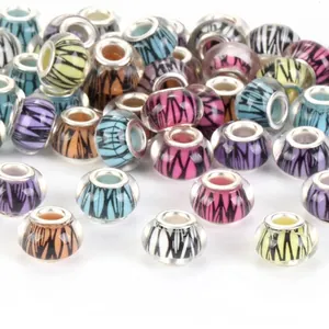 Detailed view of assorted multi-colored glass beads with abstract wing patterns for DIY jewelry