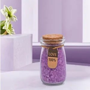 Primer plano de un frasco de cristal de sales de baño moradas con tapón de corcho