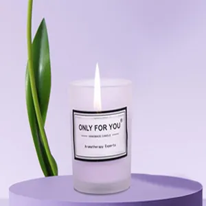 Primer plano de una vela aromática de vidrio esmerilado violeta encendida con texto