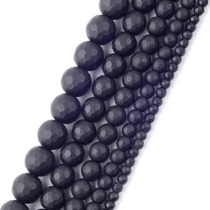 Détail macro de perles en pierre noire mate à facettes de plusieurs tailles pour DIY