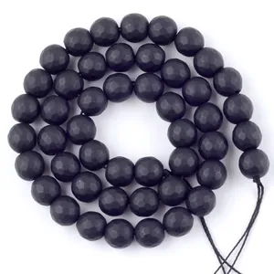 Détail macro montrant la texture mate facettée des perles de pierre noire pour bijoux DIY.