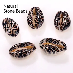 Macro view of natural cowrie shell beads with black geometric patterns for DIY jewelry