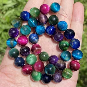 Primo piano di una mano che regge perline rotonde colorate in occhio di tigre per DIY.