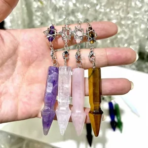 Close-up of natural crystal arrow pendulum pendants with hexagram charms held in hand
