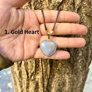 Close-up of a natural angel stone heart pendant with gold-plated trim on a brown cord.