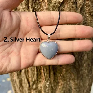 Macro detail of a natural heart-shaped blue angel stone pendant held in hand outdoors