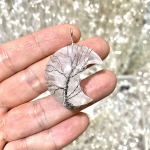 Close-up detail of white crystal moon pendant with wire-wrapped tree of life design.