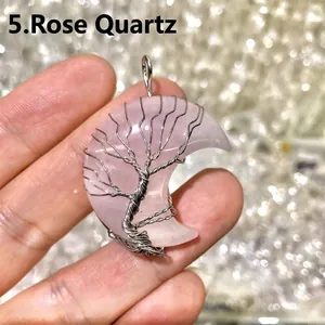 Close-up of a rose quartz crescent moon pendant with silver wire-wrapped tree of life design.