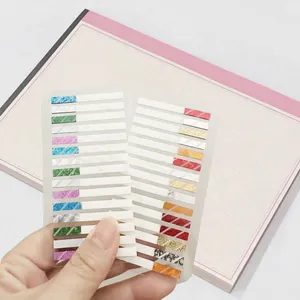 Mano che tiene adesivi indice laser colorati per l'organizzazione di quaderni e lo studio
