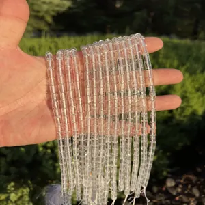 Close-up detail of transparent cylindrical clear quartz beads held in hand outdoors