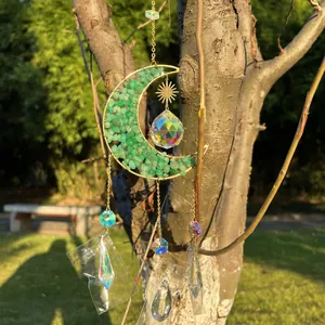 Dettaglio di acchiappasole luna in cristallo verde con gocce sfaccettate al sole.
