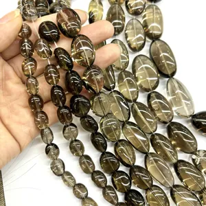 Natural polished smoky quartz oval beads strands held in hand for DIY jewelry making