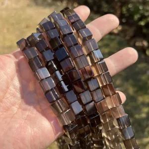 Makro-Detail von natürlichen, lichtdurchlässigen Rauchquarz-Würfelperlen in der Hand
