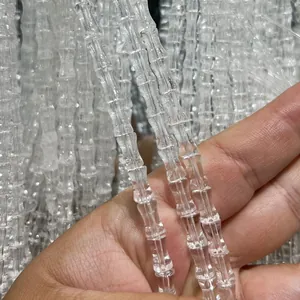 Gros plan de perles en quartz clair naturel en forme de bambou montrant la transparence.