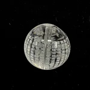 Primer plano de una cuenta de cristal natural con escritura budista grabada en relieve