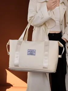 Detailaufnahme einer cremefarbenen wasserdichten Reisetasche, die von einem Model gehalten wird
