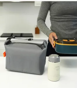 Close-up view of gray insulated lunch bag with meal prep accessories in a kitchen