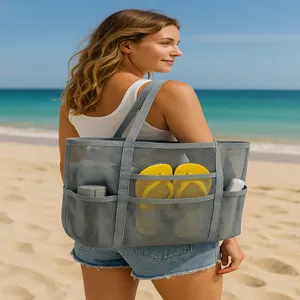 Spacious grey mesh beach storage tote bag carried by a model on a sunny sandy beach