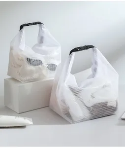 Dos bolsas organizadoras de malla blanca con asas de hebilla negra para viaje.