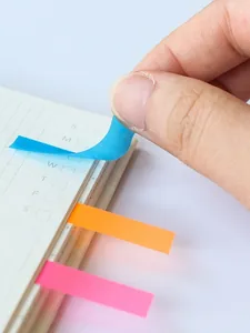 Dettaglio di una mano che stacca una linguetta adesiva blu trasparente da un taccuino