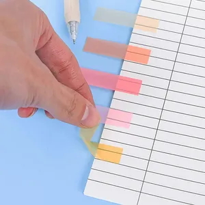 Translucent Morandi color index tabs being applied to a paper notebook page by hand