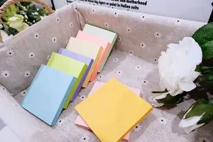 Vista detallada de notas adhesivas de colores macaron apiladas en una cesta floral
