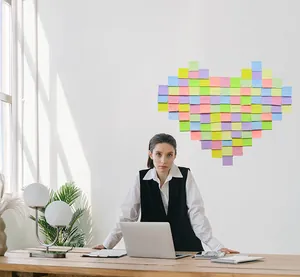 Notas adhesivas cuadradas de colores macaron en forma de corazón en pared de oficina