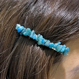 Close-up view of irregular natural blue crystal gravel on a sleek metal one-word hair clip.