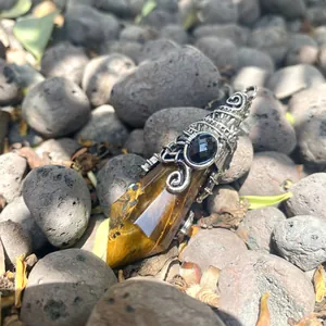 Close-up of vintage hexagonal tiger eye pendant with silver bat wing metal detail.