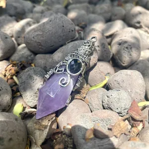 Close-up of a vintage hexagonal purple crystal pendant on natural stones.