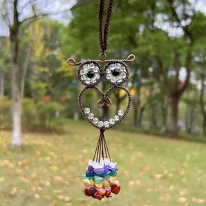 Close-up of handmade wire-wrapped owl pendant with colorful chakra crystal beads