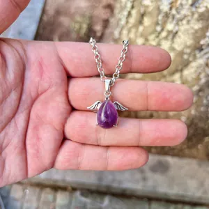 Macro view of a natural purple amethyst angel wing pendant necklace on a silver chain