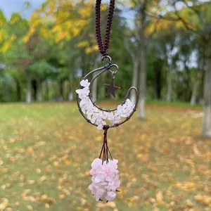Close-up detail of handmade moon hanging ornament with wire-wrapped rose quartz stones