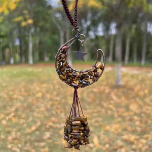 Macro view of handmade copper wire moon pendant filled with natural Tiger's Eye stones