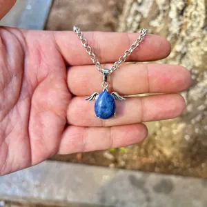Detailed view of a natural blue stone pendant with silver angel wings on a chain