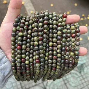 Multiple strands of natural dragon blood jasper round beads held in hand for DIY jewelry
