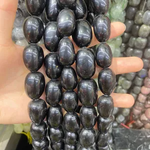 Nahaufnahme der glatten Textur schwarzer ovaler Natursteinperlen für DIY-Schmuckstücke