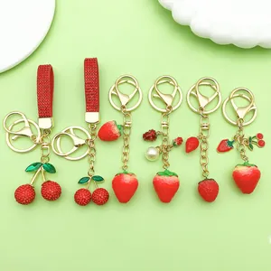 Detailed macro view of cherry and strawberry fruit keychains with red rhinestone straps.