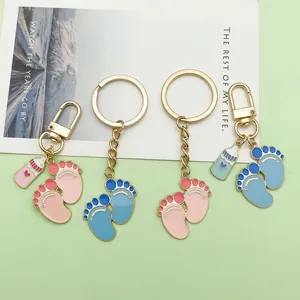 Detailed view of cute enamel baby feet and milk bottle keychains in pink and blue colors