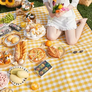 Waterproof yellow and white checkered picnic mat for outdoor camping and beach trips.