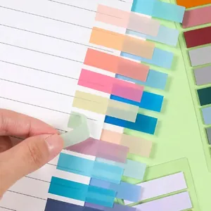Hand applying a semi-transparent Morandi color index tab to a lined paper notebook