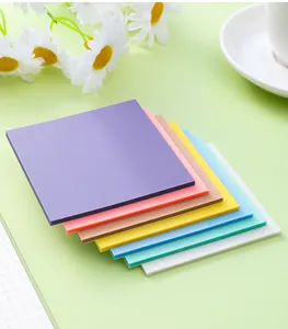 Primo piano di foglietti adesivi trasparenti color Morandi impilati su sfondo verde