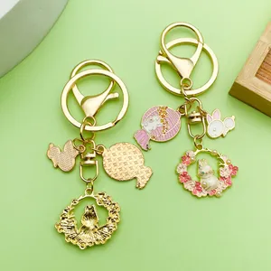 Detalle de llaveros de conejo en metal dorado con dijes de esmalte de flores de cerezo.