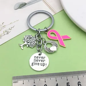Primer plano de llavero Never Give Up con cinta rosa y amuleto de árbol de la vida