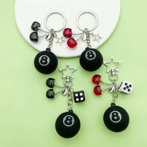 Close-up of resin cherry and black 8-ball keychains with star and dice charms.