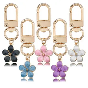 Close-up detail of five colorful enamel flower keychains with elegant gold-toned metal clasps